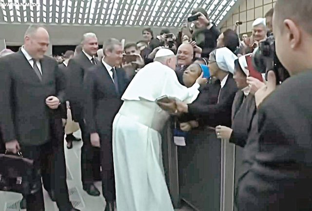 8일 바티칸 성베드로 성당에서 프란치스코 교황이 볼키스를 부탁하는 수녀에게 “키스해 줄 테니 가만히 계세요. 깨물면 안 돼요”라고 농담한 후 다가가 뺨에 입을 맞추고 있다. 미국의소리(VOA) 화면 캡처