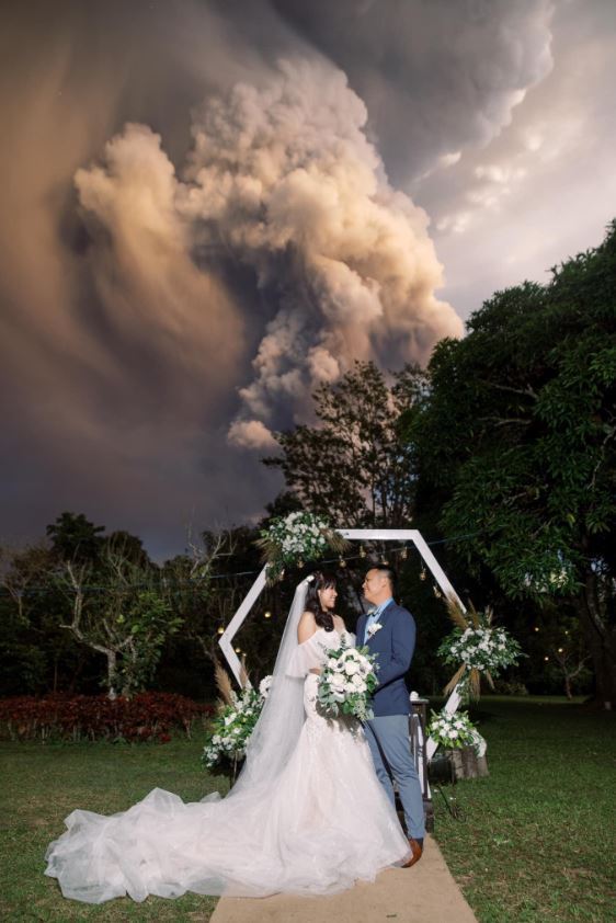 12일 화산재를 분출하는 탈 화산을 배경으로 결혼식을 올린 치노 배플러·캣 배플러 부부.<출처=CNN, 랜돌프 에번 트위터>