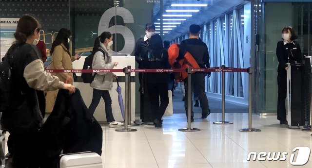 지난 27일 밤 김포공항에서 마스크를 쓴 승객들이 제주행 항공편에 탑승하고 있다. © News1