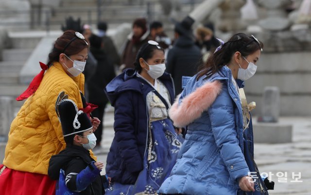 서울 경복궁에서 한복을 입은 한 관광객들이 마스크를 쓰고 있다.