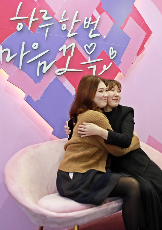 27일 오전 서울 중구 롯데백화점 본점에 설치된 ‘마음 꼬옥 사진관’을 찾은 손님들이 서로 포옹하며 사진을 찍고 있다. 롯데백화점 제공