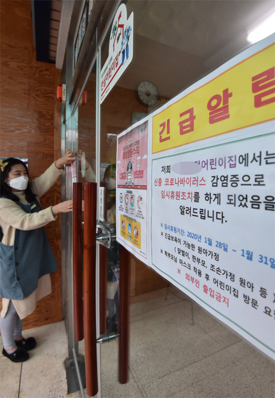 28일 경기 평택시의 한 어린이집에서 교사가 마스크를 쓴 채 입구에 휴원 안내문을 붙이고 있다. 우한 폐렴 4번째 확진자가 나온 평택시에서는 28일부터 31일까지 어린이집과 유치원이 임시 휴원한다. 평택=뉴시스