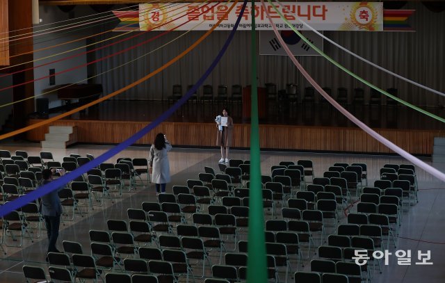 한 졸업생이 텅 빈 강당에서 가족들과 기념 사진을 촬영하고 있다.