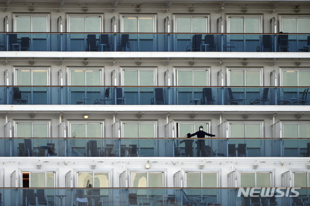 [요코하마=AP/뉴시스]다이아몬드 프린세스호에 머물고 있는 한 승객이 마스크를 쓴 채 손체조를 하고 있다.