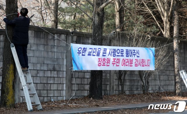 3차 우한 교민 수송을 하루 앞둔 11일 오후 임시 생활시설로 지정된 경기도 이천시 합동군사대학교 국방어학원 인근 도로에서 한 시민이 우한 교민과 관련된 현수막을 부착하고 있다. 2020.2.11/뉴스1 © News1