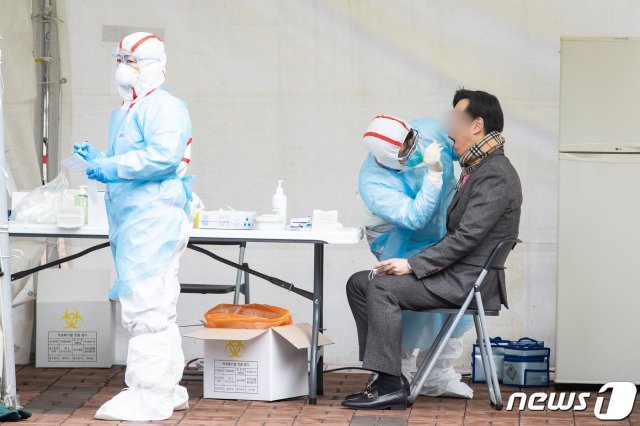 신종 코로나바이러스 감염증(코로나19) 확진자가 1,000명을 돌파한 26일 서울 강동구 명성교회 앞에 마련된 임시 선별진료소에서 주민들이 진료를 받고 있다. © News1