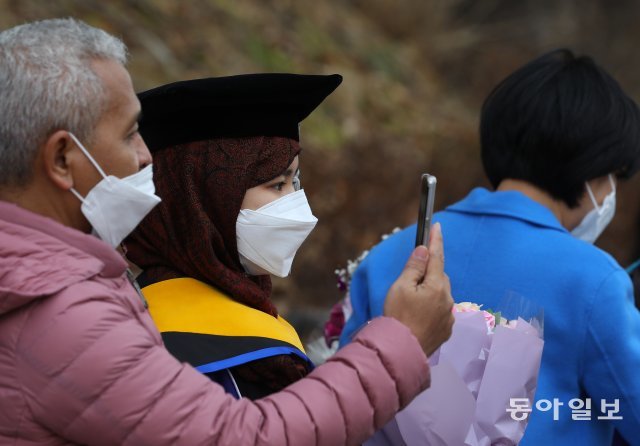외국인 졸업생이 마스크를 쓰고 기념 촬영을 하고 있습니다.