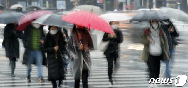 봄을 재촉하는 비가 내리는 25일 오전 서울 종로구 광화문 네거리에서 마스크와 우산을 쓴 시민들이 출근하고 있다. © News1