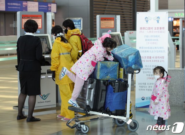 신종 코로나바이러스 감염증(코로나19) 확진자가 급증한 가운데 27일 오후 인천국제공항 2터미널에서 마스크와 우비를 착용한 가족이 출국장으로 향하고 있다.  © News1