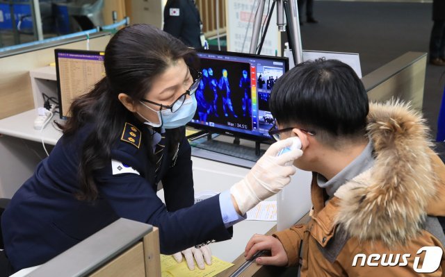 인천국제공항 제1여객터미널을 통해 입국하던 한 여행객이 열화상카메라에 감지돼 방역당국 직원이 체온을 확인하고 있다.  2020.1.24/뉴스1 © News1