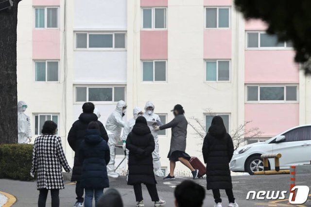 8일 오전 대구시 달서구 신종 코로나바이러스 감염증(코로나19)으로 처음으로 코호트격리된 한마음아파트에서 한 확진자가 캐리어를 끌고 생활치료센터행 버스로 향하고 있다. 국내에서 처음으로 코로나19로 코호트격리된 이 아파트에는 입주민 142명 중 확진자가 46명이 나왔다. 또한 입주민 중 66.19%인 94명이 신천지 교인으로 알려졌다. 뉴스1