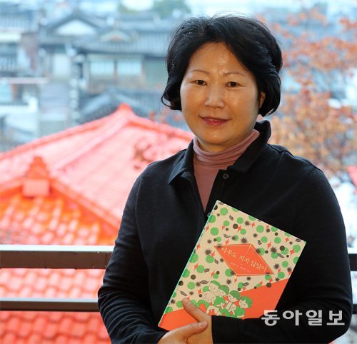황선미 작가가 9일 서울 종로구 가회동 한옥들을 배경으로 자신의 그림책 ‘아무도 지지 않았어’를 들고 있다. 전영한 기자 scoopjyh@donga.com