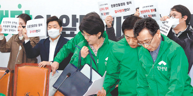 박주현 민생당 공동대표(앞줄 왼쪽)가 18일 국회에서 당 지도부와 함께 범여권 비례연합정당 참여를 의결하던 도중 이에 반대하는 바른미래당계 당직자들이 피켓 시위를 벌이자 황급히 자리를 옮기고 있다. 뉴스1