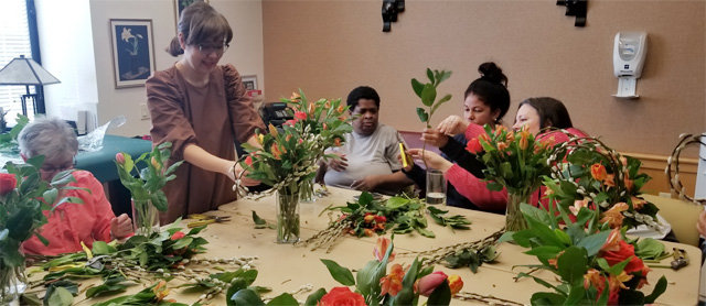 지난달 24일(현지 시간) 미국 뉴욕 브롱크스의 캘버리병원에서 한국계 비영리 문화복지단체 ‘이노비(EnoB)‘ 소속 자선봉사자인 꽃꽃이 전문가 채정아 씨(왼쪽에서 두 번째)가 80대 노모를 간병하고 있는 디디 후퍼 씨(왼쪽에서 세 번째) 등 가족 간병인에게 꽃꽃이 요령을 설명하고 있다.