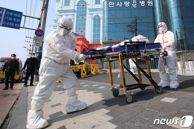 환자와 직원 등 70여 명의 신종 코로나바이러스 감염증(코로나19) 확진자가 발생한 대구 서구 비산동 한사랑요양병원에서 19일 오전 보호복을 착용한 119구급대원이 확진자를 구급차로 옮기고 있다. 방역당국은 이날 오전 한사랑요양병원 확진자 30여 명을 119구급차에 1명씩 태워 대구의료원으로 이송할 계획이다. 2020.3.19/뉴스1 © News1