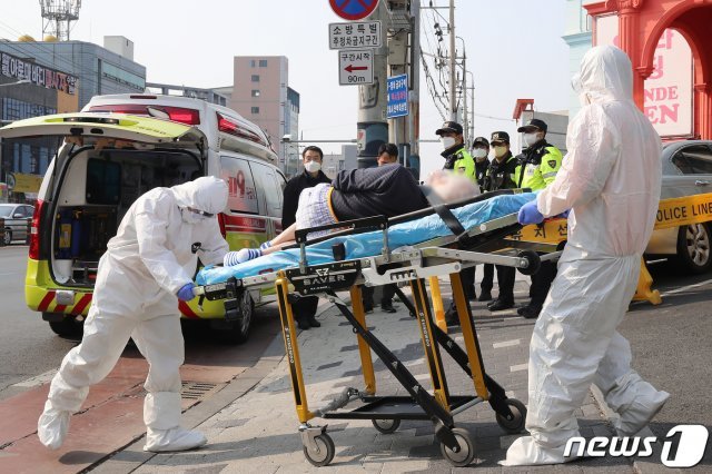 환자와 직원 등 70여 명의 신종 코로나바이러스 감염증(코로나19) 확진자가 발생한 대구 서구 비산동 한사랑요양병원에서 19일 오전 보호복을 착용한 119구급대원이 확진자를 구급차로 옮기고 옮기고 있다. 20.3.19/뉴스1 © News1