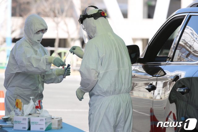 전날 강풍으로 일시 중단됐던 차량선별진료소가 다시 운영에 들어간 20일 오전 대구 수성구 대흥동 대구스타디움 P3 주차장에 마련된 선별진료소에서 수성구보건소 관계자들이 코로나19 의심 증상으로 방문한 시민의 검체를 채취하고 있다. 2020.3.20/뉴스1 © News1