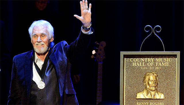 2013년 ‘컨트리 음악 명예의 전당’에 오른 케니 로저스가 미국 테네시주 내슈빌 명예의 전당 무대에서 관중에게 손을 흔들고 있다. 그래미상을 3차례 수상한 그는 팝, 컨트리, 포크 등 장르를 넘나드는 노래로 사랑받았다. AP 뉴시스