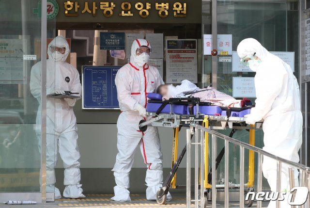 대구 서구 비산동 한사랑요양병원에서 19일 오전 보호복을 착용한 119구급대원이 확진자를 구급차로 옮기고 옮기고 있다. 뉴스1