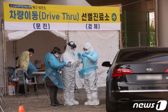 부산 북구 화명운동장 주차장에 마련된 차량이동 선별진료소(드라이브 스루 선별진료소)를 지난 6일 찾은 한 시민이 신종 코로나 바이러스 감염증(코로나19) 검체 체취를 받고 있다./뉴스1 © News1