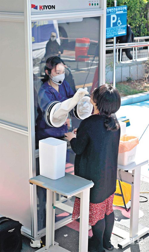1명 검사에 15분… 초스피드 ‘워킹스루’ 등장 31일 부산 남구보건소 앞 부스에서 신종 코로나바이러스 감염증(코로나19) 의심 환자의 검체를 의료진이 부스 안에서 손만 내놓은 채 채취하고 있다. 피검사자가 부스로 들어가던 기존 방식과 달리 의료진이 안에 들어가 별다른 소독이 필요 없다. 이에 따라 25분가량 걸리던 검사 시간은 15분으로 단축됐다. 이 장비는 남구보건소 안여현 의무사무관이 고려기연과 협업해 개발했다. 부산=박경모 기자 momo@donga.com