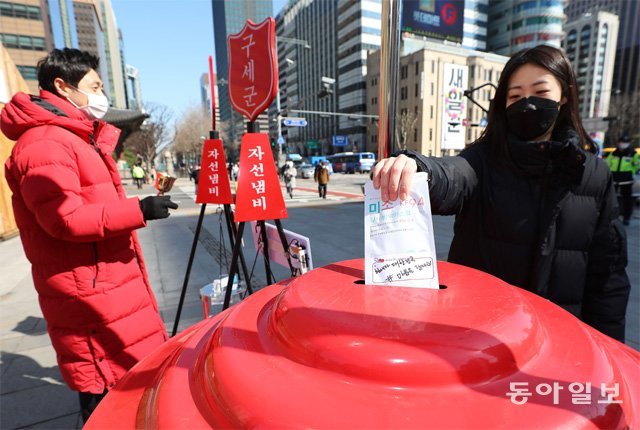 서울 광화문광장에 설치된 구세군 자선냄비에 마스크를 쓴 시민이 보건용 마스크를 기부하고 있다. 전영한 기자 scoopjyh@donga.com