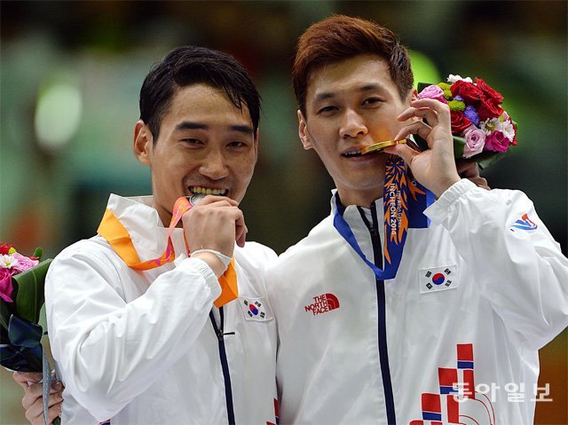구본길(오른쪽)과 김정환이 2014 인천 아시아경기 펜싱 사브르 남자 개인전에서 각각 금메달, 은메달을 딴 뒤 메달을 깨물고 있다. 동아일보DB