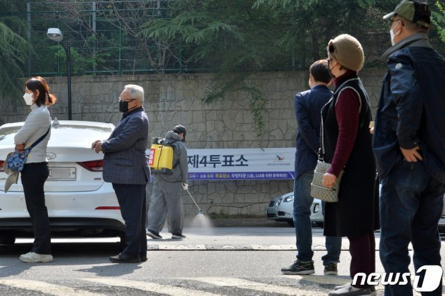 제21대 국회의원 선거일인 15일 오전 경북 포항시 북구 용흥동 우방아파트 단지 내에 마련된 투표소에서 포항시 방역팀이 투표장 주변에 대한 소독작업을 하고 있는 가운데, 유권자들이 순서를 기다리고 있다. 2020.4.15/뉴스1 © News1