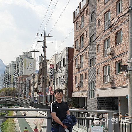 서울 도봉구 방학천문화예술거리 ‘문화인마을 3차’(오른쪽 붉은 벽돌 건물) 앞에 선 황선무 씨. 그는 배우이면서 코미디 
퍼포먼스 극단 ‘우카탕카’ 대표이기도 하다. 문화인마을 3차는 황 씨 같은 배우를 비롯해 독립영화 감독, 웹툰 작가, 가수 등 
문화예술계 종사자 13가구가 살고 있는 맞춤형 임대주택이다. 황재성 기자  jsonhng@donga.com