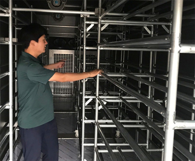 스마트팜 시스템 개발업체 디자인파머스의 컨테이너형 원격 제어 스마트팜을 관계자가 살펴보고 있다. 농업기술실용화재단 제공