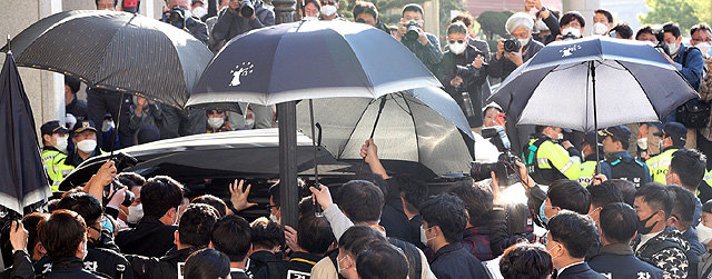 우산 경호 27일 광주지법 관계자가 재판을 마치고 출발하는 전두환 전 대통령의 차량 주변을 둘러싸고 계란 투척에 대비하기 위해 우산을 펼쳐들고 있다. 차량이 법원 청사를 벗어나자 한 시민이 차량을 향해 계란을 던졌다. 사진공동취재단