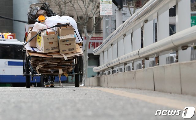 26일 오전 대구 북구 경대교 인근 도로에서 한 노인이 수레 가득 파지를 싣고 무거운 발걸음을 옮기고 있다. 2020.3.26/뉴스1 © News1