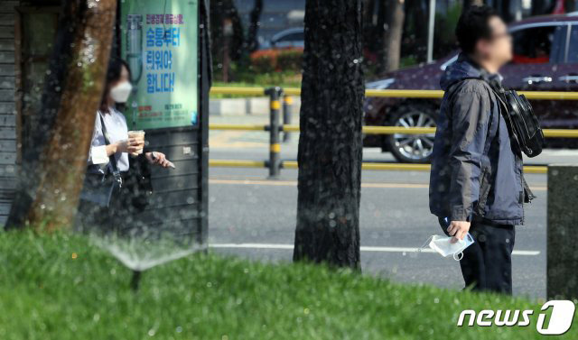 24절기중 7번째 절기로 여름이 시작되었음을 알리는 ‘입하(立夏)’를 하루 앞둔 4일 서울 을지로입구역 인근에서 마스크를 벗은 시민이 스프링클러 앞 도보를 지나고 있다. 2020.5.4 © News1
