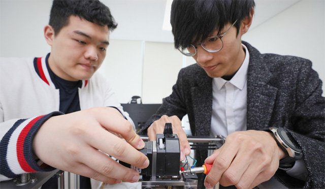 인하대 대학원에 재학 중인 ㈜에나스 대표이사 권혁배 씨(오른쪽)가 직원과 함께 슈퍼 엔지니어링 플라스틱을 사용할 수 있는 3D 프린터를 살펴보고 있다. 인하대 제공