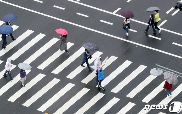 비가 내리는 지난 15일 서울 종로구 정부서울청사에서 바라본 세종대로 광화문네거리에서 우산을 쓴 시민들이 횡단보도를 건너고 있다. © News1