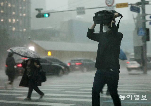 18일 오후 4시경 서울 세종로 네거리에서 하늘이 어두워지며 갑자기 폭우가 쏟아지자 미처 우산을 준비못한 행인은 가방으로 급히 비를 막아보지만 역부족이다. 전영한 기자 scoopjyh@donga.com