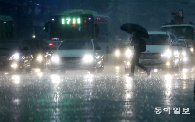18일 오후 서울 세종로 네거리에서 하늘이 컴컴해지면서 도로에 폭우가 내리자 시민들의 발걸음이 빨라지고 있다. 전영한 기자 scoopjyh@donga.com