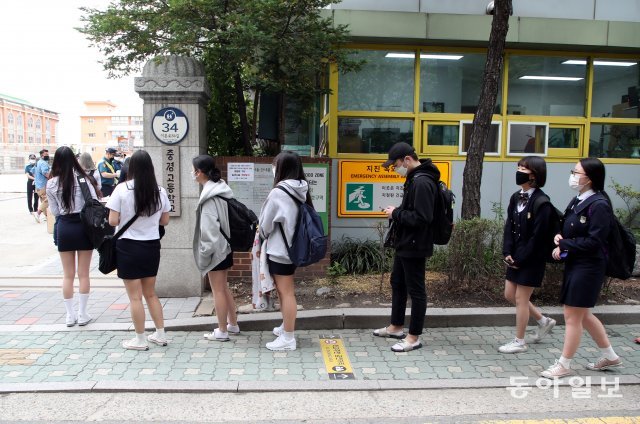 20일 오전 서울 시내의 한 고등학교 3학년 학생들이 교문 앞에서 발열 확인을 하기 위해 줄을 서 있다.