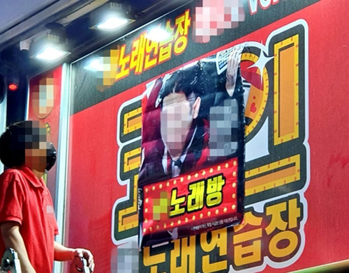 22일 밤 서울 마포구 홍익대 인근에 있는 한 코인노래방의 직원이 사다리를 타고 올라가 코인노래방 간판 위에 일반노래방이라고 안내하는 포스터를 붙이고 있다. 뉴스1