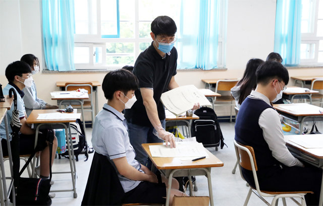 경기도의 한 고교에서 마스크를 쓴 교사가 비닐장갑을 끼고 시험지를 나눠주고 있다.