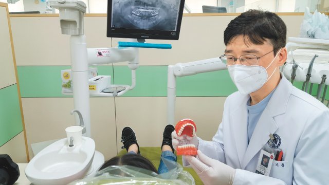 이기준 연세대 치대 교수가 치아 모형을 들고 환자에게 치료과정을 설명하고 있다. 연세대 치대 제공