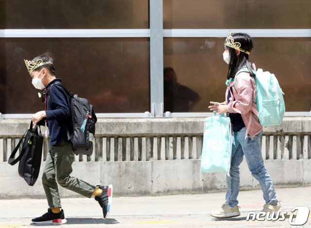 27일 경기 수원 팔달구 한 초등학교에서 신종 코로나바이러스 감염증(코로나19) 예방을 위해 마스크를 쓴 1학년 학생들이 입학을 축하하는 의미로 왕관을 쓰고 하교하고 있다./뉴스1 © News1
