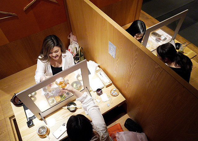 투명 가림막이 설치된 일본 도쿄의 한 주점에서 시민들이 대화를 나누고 있다. 신종 코로나바이러스 감염증의 여파로 일본의 대부분 오프라인 음식점과 주점은 비말 감염을 막기 위해 투명 가림막을 세웠다. 아사히신문 제공