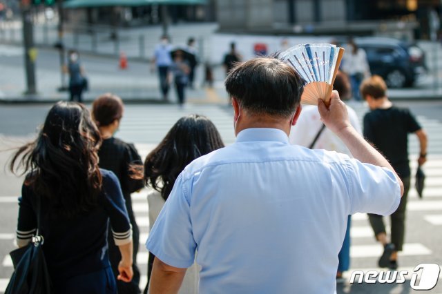 8일 오후 서울 중구 회현사거리에서 한 시민이 부채로 햇빛을 가린 채 걸어가고 있다./뉴스1 © News1