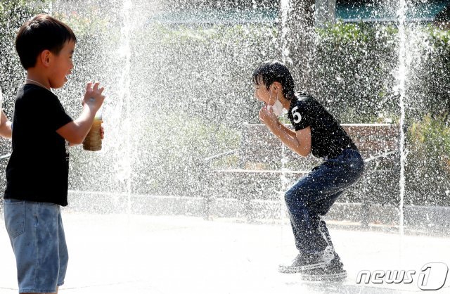 전국적으로 폭염주의보가 내려진 9일 오후 서울 마포구의 한 공원에 설치된 분수대에서 마스크를 쓴 한 어린이가 시원한 물줄기를 맞으며 더위를 식히고 있다. 2020.6.9 © News1