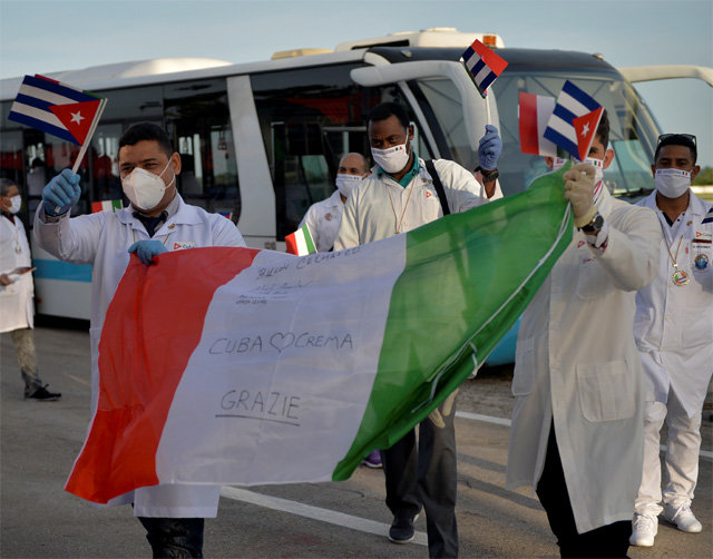 흰색 의료용 가운을 입은 쿠바 의료진이 쿠바와 이탈리아 국기를 들고 8일 수도 아바나의 호세마르티 국제공항에 도착한 모습. 아바나=AP 뉴시스