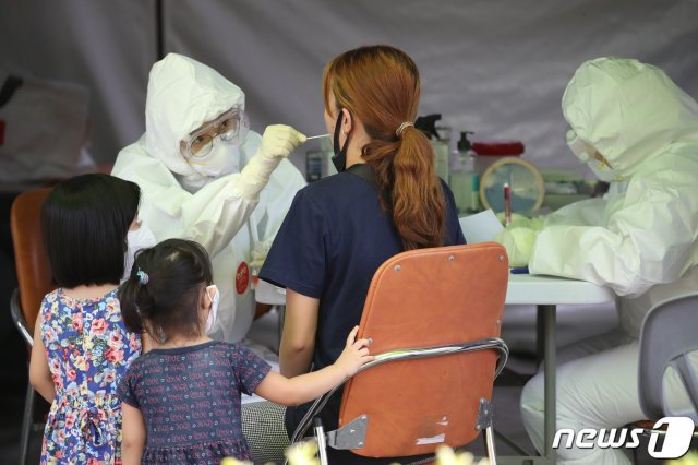 선별진료소에서 방호복을 입은 의료진이 신종 코로나바이러스 감염증(코로나19) 검사를 위해 방문한 가족의 검체를 채취하고 있다. © News1