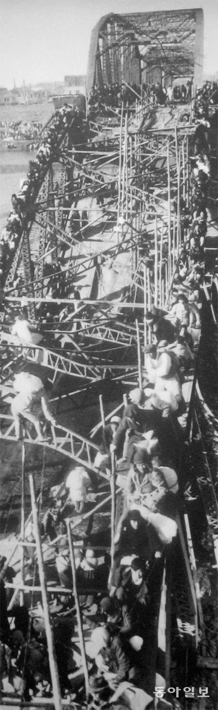 1950년 12월 AP통신 맥스 데스퍼 기자가 대동강 다리 잔해를 기어올라 강을 건너는 피란민을 촬영한 사진. 동아일보DB