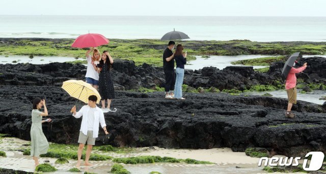 제주 전역에 비가 내릴 것으로 예보된 17일 오후 제주시 한림읍 협재해수욕장에서 우산을 쓴 관광객들이 여유로운 시간을 보내고 있다. 기상청은 이날 오후부터 시작된 비가 19일까지 계속될 것으로 예보했으며, 19일 오전 6시까지 예상 강수량은 80~150mm다. 제주는 지난 10일부터 장마철에 접어들었다. 2020.6.17 © News1