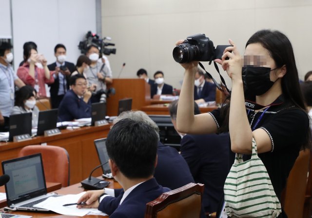 국회에서 열린 한 상임위원회 회의실에서 보좌진이 제법 큰 디지털 카메라로 사진을 찍고있다.